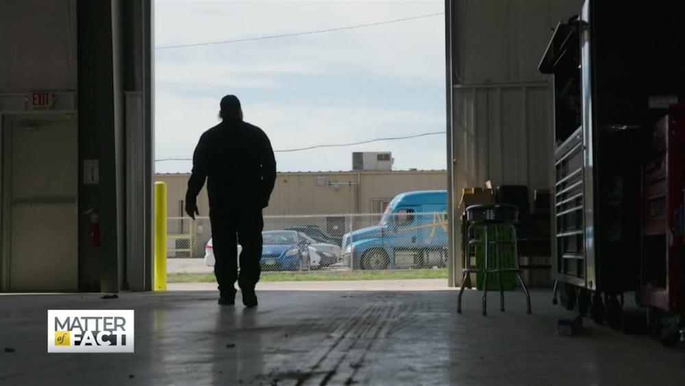 The silhouette of a burly man as he walks away in a large warehouse.